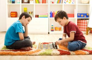Let me show you a move - kids playing chess sitting on the floor in their room